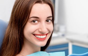 Satisfied broadly smiling young woman in a dental chair.